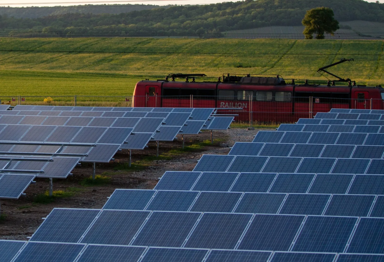 Solar panels across a landscape with a train passing behind